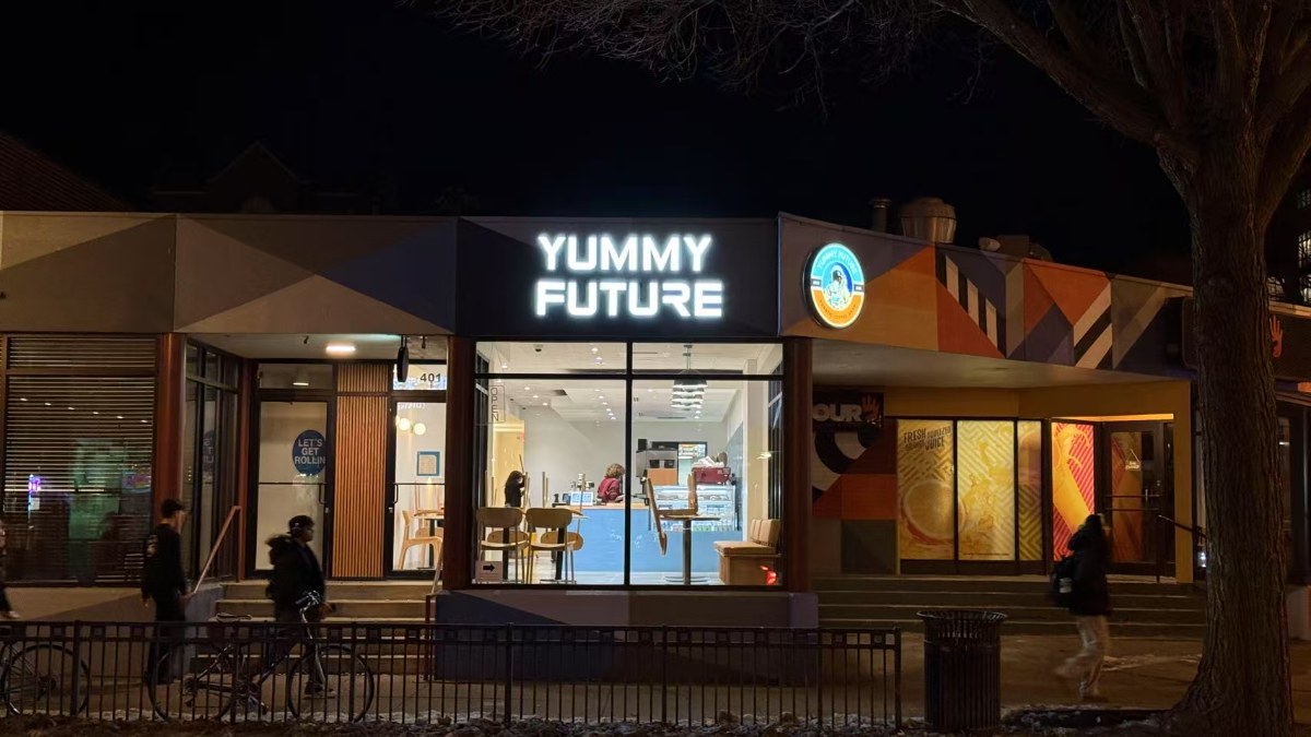 Lit Yummy Future storefront at 401 East Green Street, Champaign, at night; people walking past