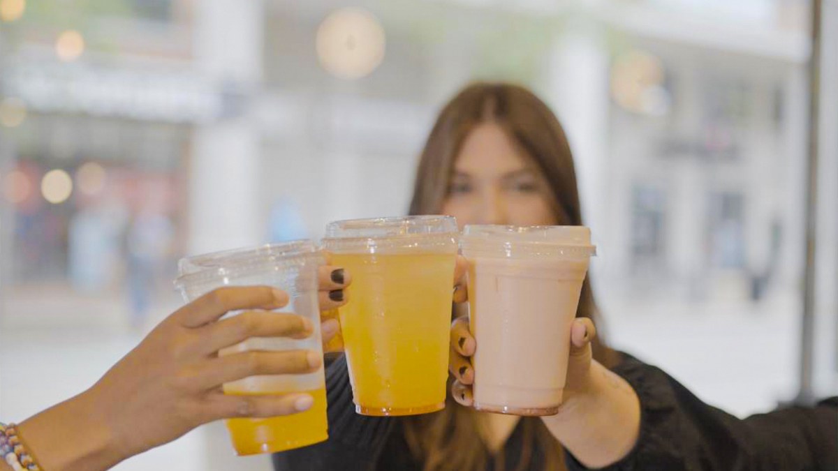 Three customers touching cups together outside the store