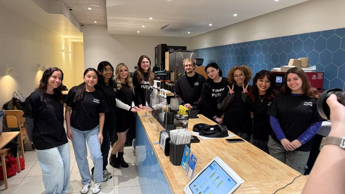 Eleven store staff in Yummy Future shirts standing along the bar at the end of a shift
