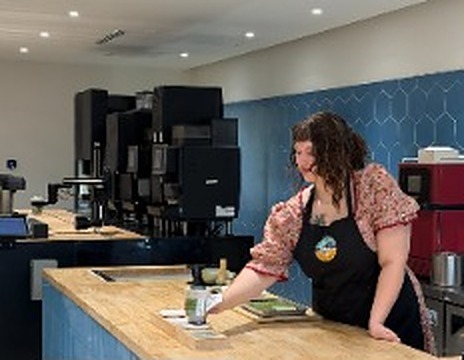 Barista at the wood counter inside the Matcha House store, blue hexagon tile wall