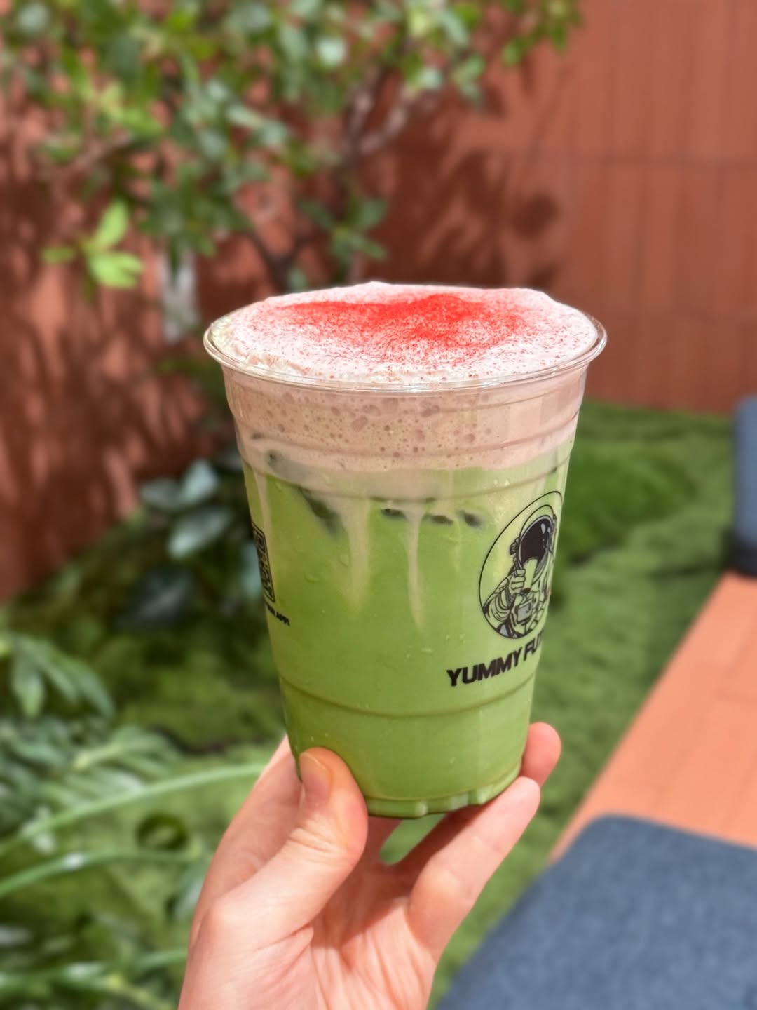 Customer holding a strawberry cream matcha against the terracotta wall